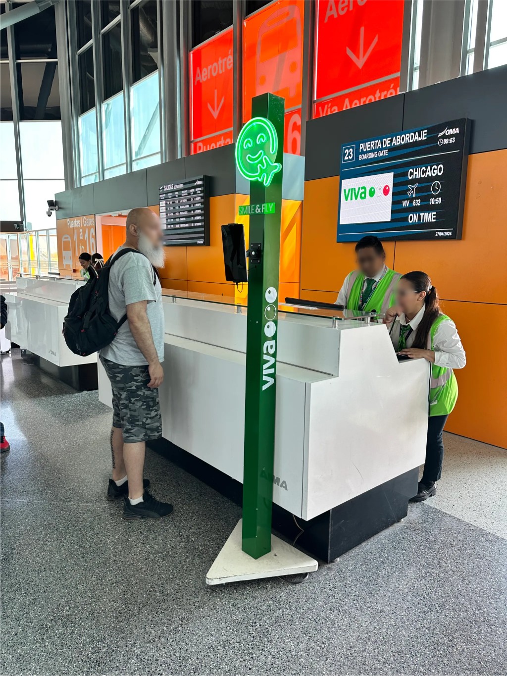 Airport check-in area with a green Fan ID kiosk beside a service counter.